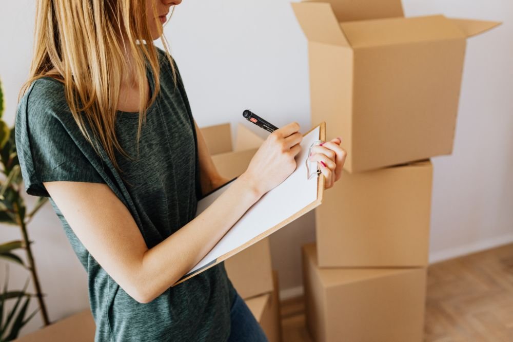 Homeowner listing packed boxes on a clipboard for a contents inventory