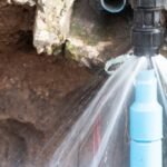 Water spraying from a burst pipe fitting inside an open wall