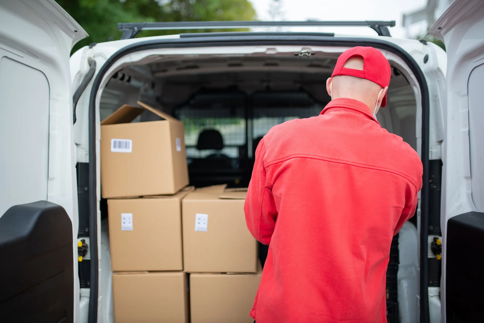 Worker loading packed cardboard boxes into the back of a van